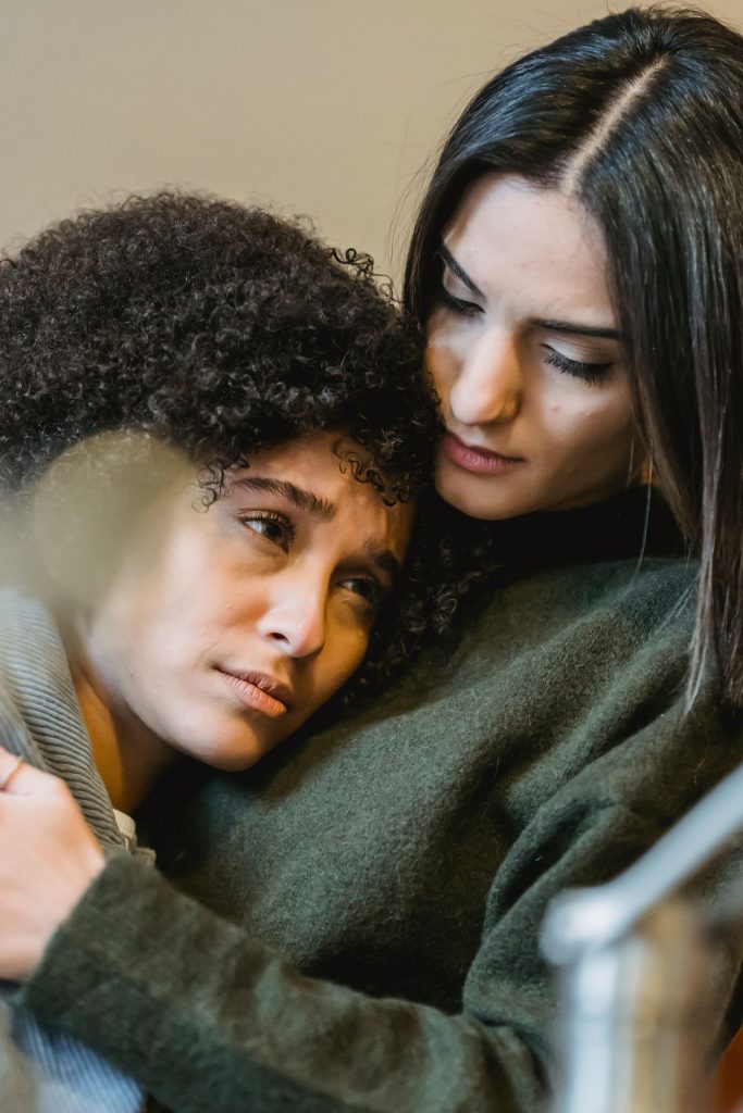 One person comforting another with a supportive embrace.