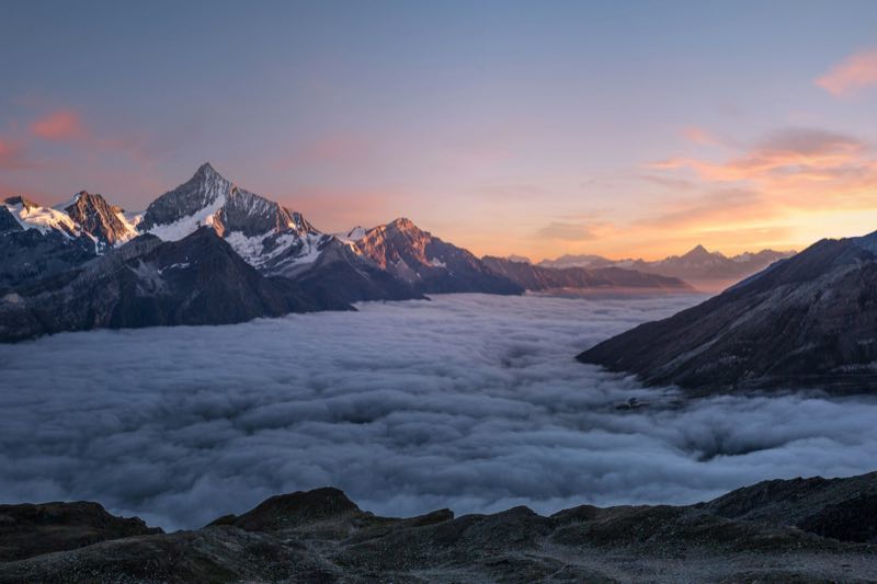 Mountain peaks rising above the clouds at sunrise
