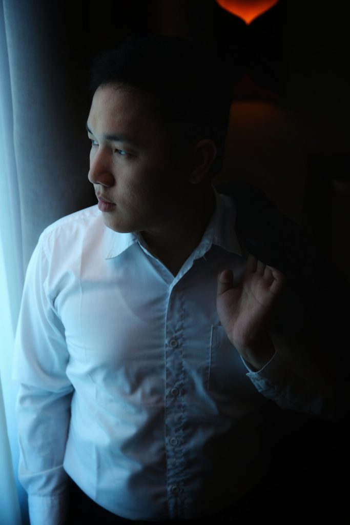 A person pausing quietly beside a window.